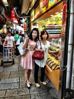 Ladies pose in front of sweetmeat stall